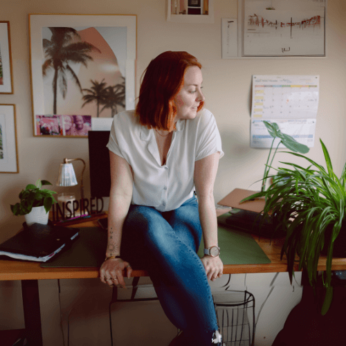 Coach Jen sitting on her desk, preparing coaching content in an inspiring workspace for building healthy habits working with clients online